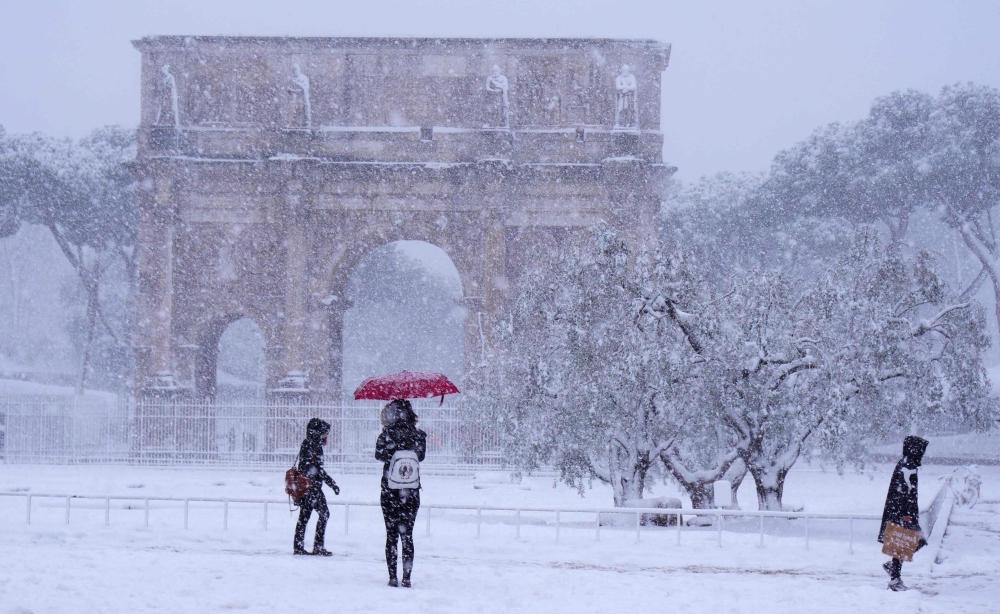 Tourists visit the Arch of Constantine during a snowfall in Rome on February 26, 2018. AFP / Vincenzo Pinto