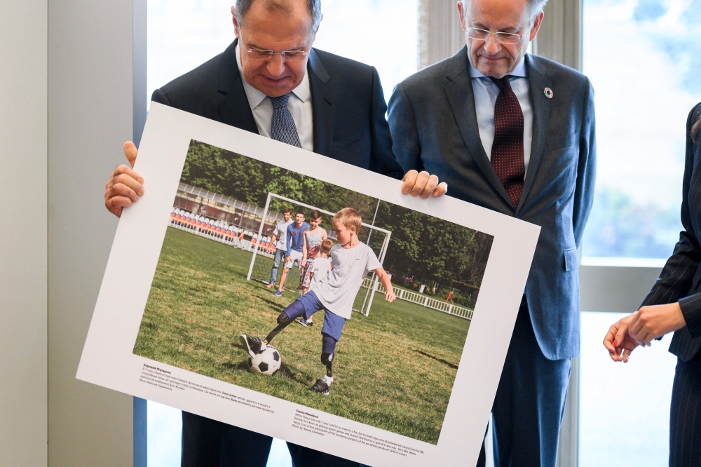 Russian Foreign Minister Sergei Lavrov (L) holds a picture next to Director-General of the United Nations Office at Geneva Michael Moller during the opening of a photo exhibition on disabled people entitled: 