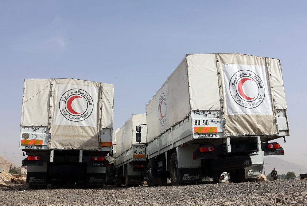 Trucks belonging to the International Committee of the Red Cross (ICRC) are seen parked on March 8, 2018, at the al-Wafideen checkpoint on the outskirts of Damascus neighbouring the rebel-held Eastern Ghouta region, as they wait for authorisation to enter