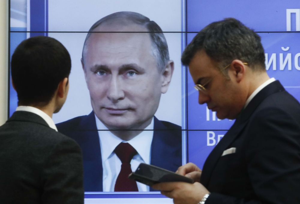 Men stand in front of a screen showing preliminary results of Russian President Vladimir Putin in the presidential election, at the headquarters of Russia's Central Election Commission in Moscow, Russia March 19, 2018. REUTERS/Sergei Karpukhin