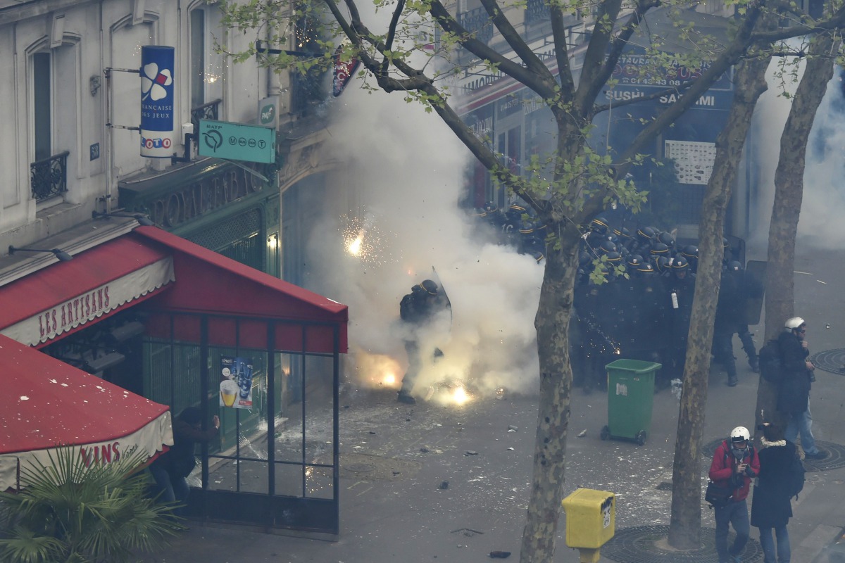 File photo of a French anti-riot police officer protecting himself from smoke grenades during clashes with protesters, April 28, 2016 in Paris (AFP) 