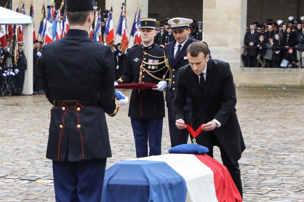 French President Emmanuel Macron (R) bows and places the posthumous medal of Commander in the Legion of Honor Order on the coffin of Lieutenant-Colonel Arnaud Beltrame, draped with the national flag, during a national ceremony on March 28, 2018 at the Hot