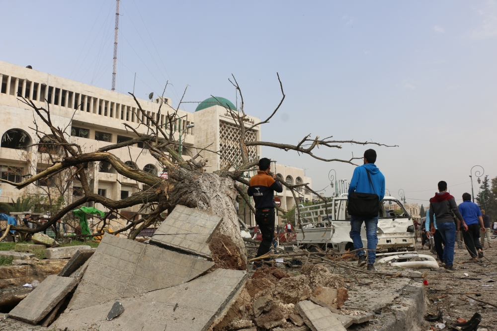 Syrians are seen near a broken down tree after a terror attack was carried out with a bomb-laden vehicle exploded, which killed 7 civilians and injured 25, in Idlib, Syria on March 24, 2018. ( Ahmed Rahhal - Anadolu
