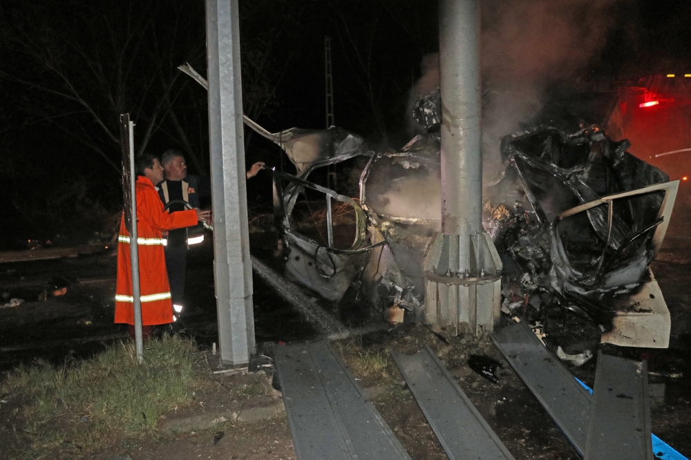 Firefighters try to extinguish fire of a wreckage of a minibus, carrying migrants, after it crashed into a light pole and caught fire in Igdir, Turkey on March 30, 2018. Bülent Mavzer - Anadolu Agency