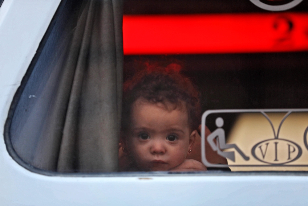 A child looks out of the window of a bus as they arrive in Qalaat al-Madiq, some 45 kilometres northwest of the central city of Hama, on April 2, 2018 after being evacuated from the Eastern Ghouta town of Douma. AFP / Omar Haj Kadour 