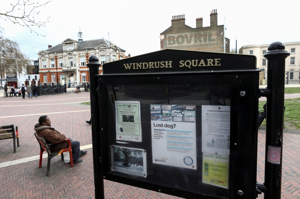 A man sits on a bench next to a sign on Windrush Square in the Brixton district of London, Britain April 16, 2018. REUTERS/Simon Dawson