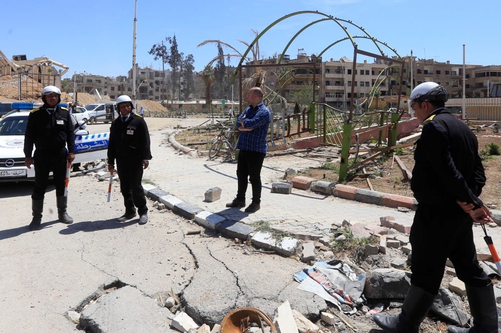 Syrian traffic police stand in the street in Douma on the outskirts of Damascus on April 16, 2018 during an organised media tour after the Syrian army declared that all anti-regime forces have left Eastern Ghouta, following a blistering two month offensiv