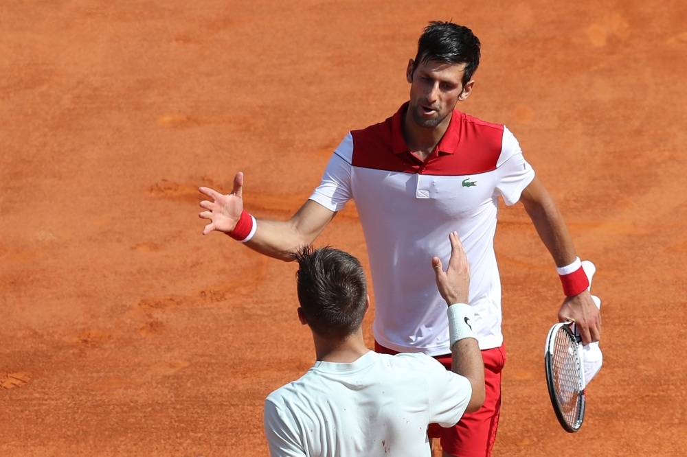 Serbia's Novak Djokovic (up) shakes hands with Croatia's Borna Coric after winning their men's single tennis match at the Monte-Carlo ATP Masters Series Tournament on April 18, 2018 in Monaco. / AFP / VALERY HACHE