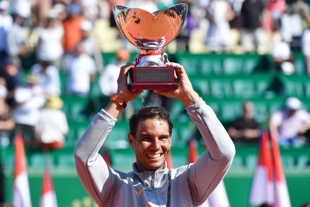 Spain's Rafael Nadal holds up the trophy as he celebrates his win over Japan's Kei Nishikori in their final match at the Monte-Carlo ATP Masters Series tournament on April 22, 2018, in Monaco.  / AFP / Yann COATSALIOU 
