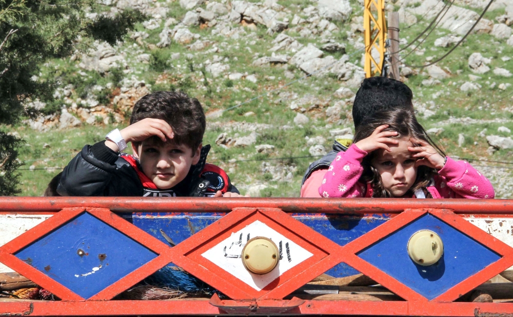 Syrian child refugees ride in the back of a pickup truck prior to their evacuation from the southern Lebanese village of Shebaa on April 18, 2018, to return home to their village of Beit Jinn in the southwestern Damascus countryside. / AFP / Ali DIA
