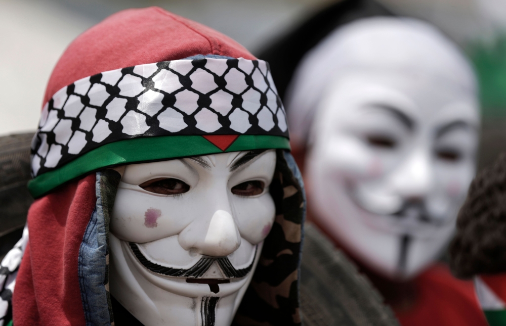 A Palestinian demonstrator wearing an Anonymous mask protests on the Israel-Gaza border, east of Gaza City in the central Gaza Strip, during the fifth straight Friday of mass demonstrations and clashes along the border with Israel on April 27, 2018.  AFP 