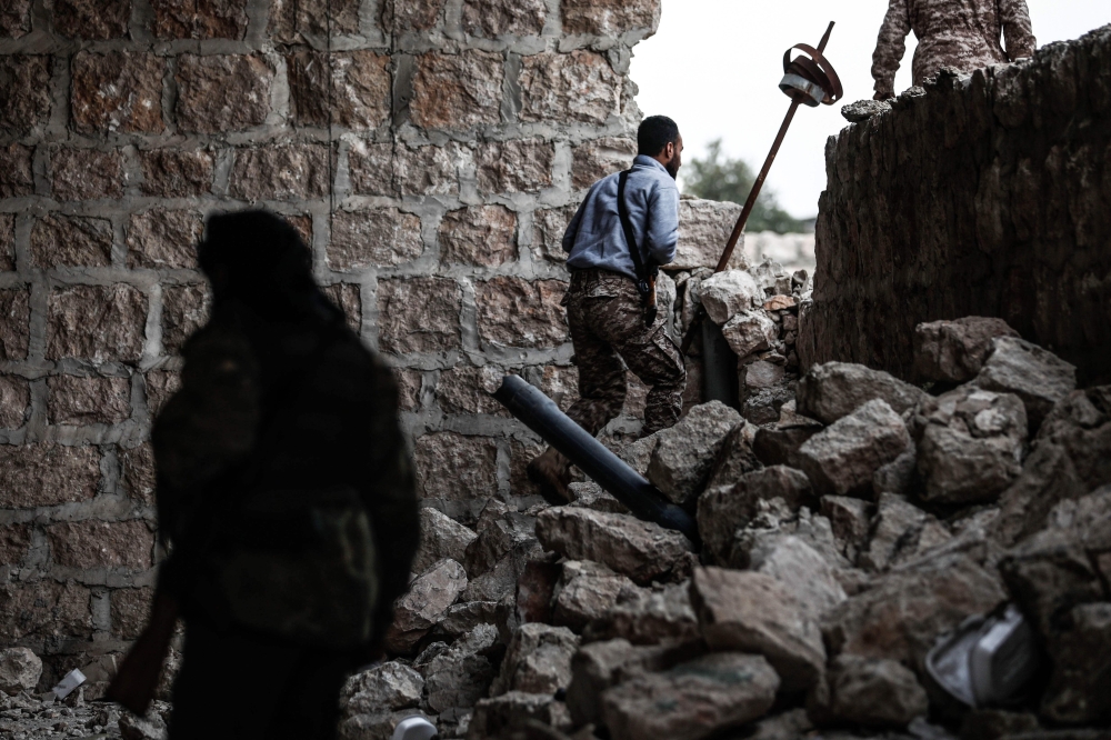 Turkish-backed Syrian fighters exit a building in Tadef, near the city of al-Bab in the northern countryside of Aleppo province on April 27, 2018. / AFP / Sameer Al-Doumy
