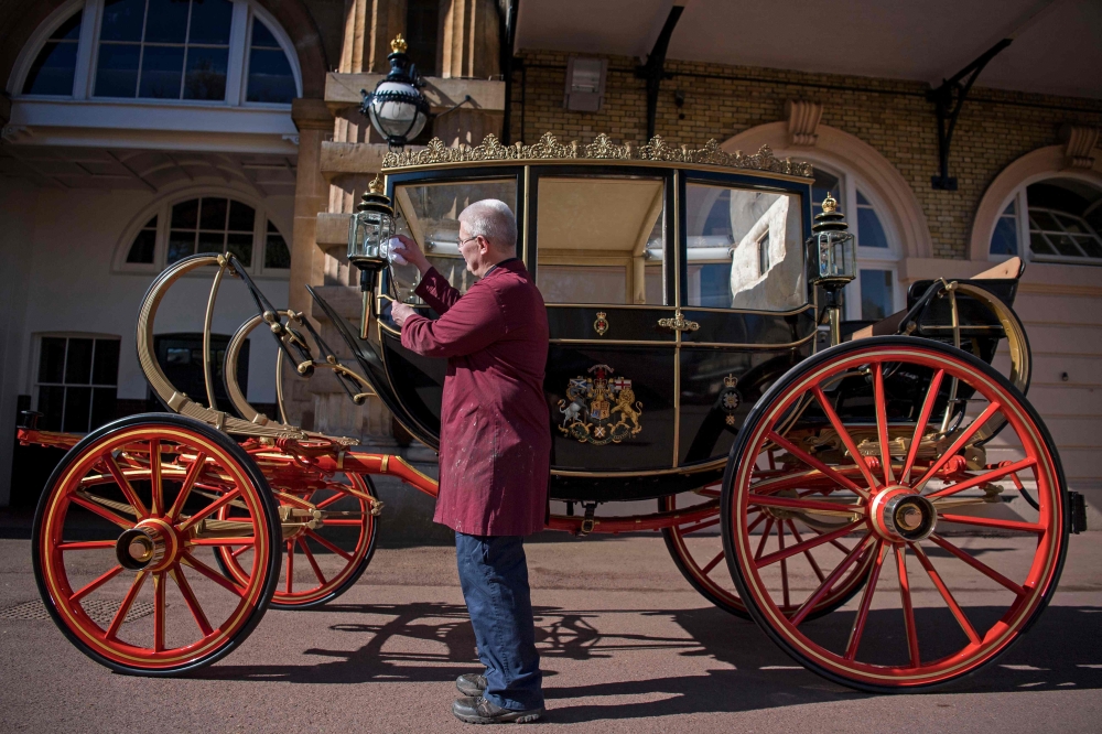 Senior Carriage Restorer, Martin Oates polishes the Scottish State Coach which will carry Britain's Prince Harry and wife Meghan Markle in wet weather along the processional route in Windsor following their marriage stands in the Royal Mews at Buckingham 