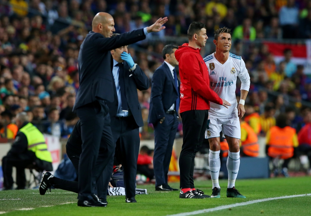 Real Madrid's Cristiano Ronaldo waits to return to the pitch after sustaining an injury as coach Zinedine Zidane gestures REUTERS/Albert Gea	
