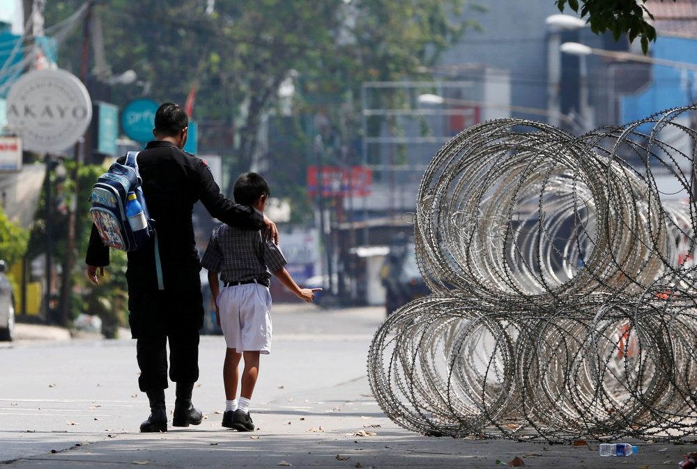 A policeman escorts a student past the front of the Mobile Police Brigade (Brimob) headquarters in Depok, south of Jakarta, Indonesia, May 9, 2018. REUTERS/Beawiharta