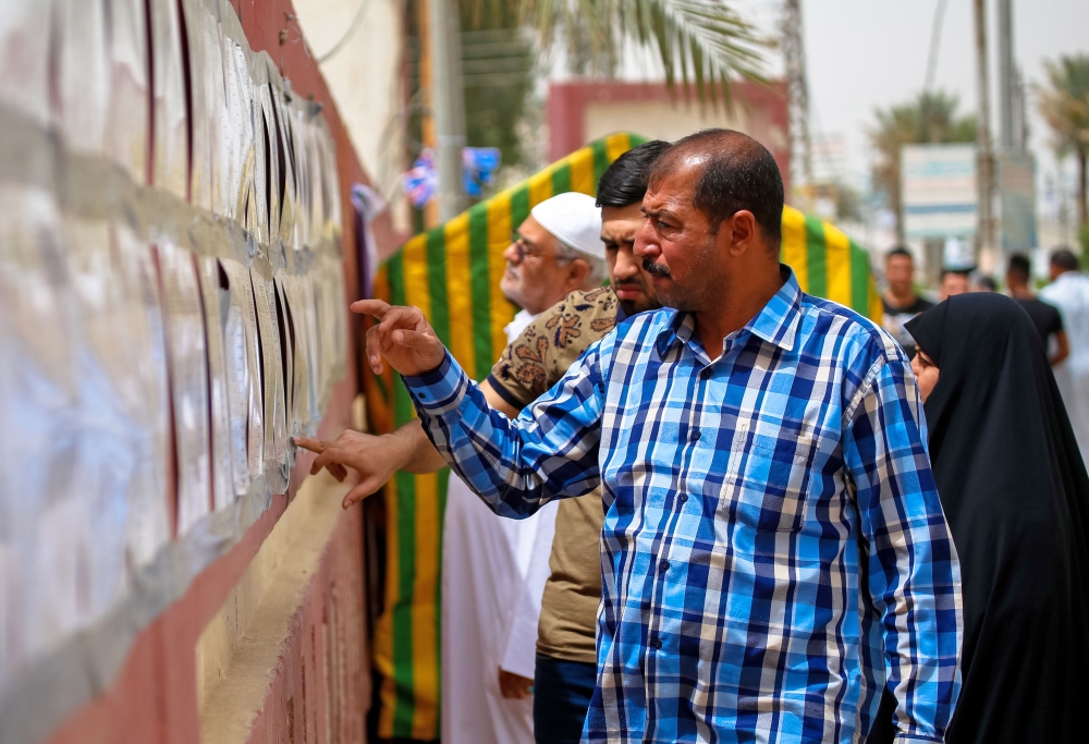 Iraqi voters read lists of candidates outside a polling station in the central holy city of Najaf on May 12, 2018 as the country votes in the first parliamentary election since declaring victory over the Islamic State (IS) group.   AFP / Haidar HAMDANI
