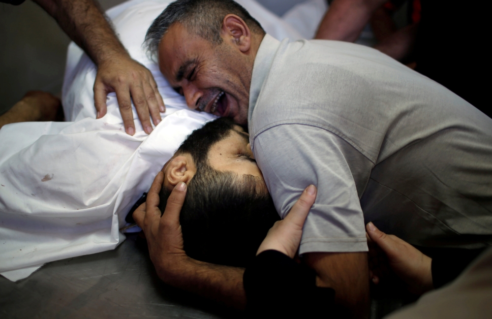 The brother of Palestinian Shaher al-Madhoon, who was killed during a protest at the Israel-Gaza border, reacts over his body at a hospital morgue in the northern Gaza Strip May 14, 2018. Reuters/Mohammed Salem