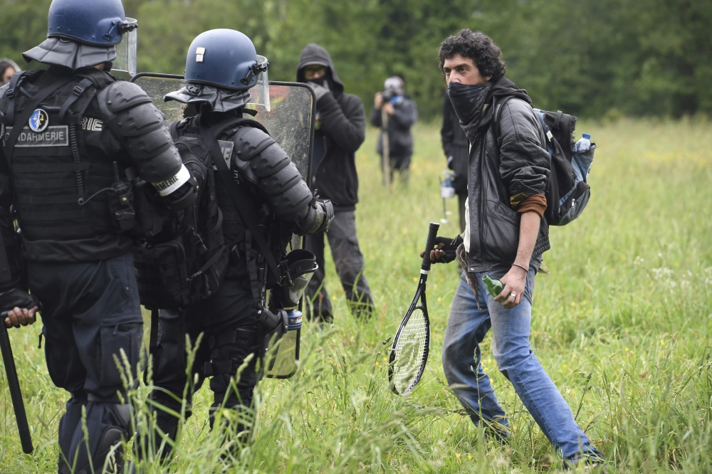 A protester faces French riot gendarmes, during the second eviction of environmental protesters from the area, known as ZAD (Zone a Defendre - Zone to defend) at the site of an abandoned airport project near the western city of Nantes, in Notre-Dame-des-L