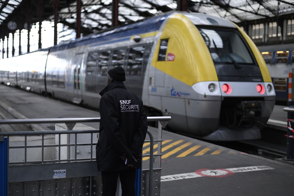 (FILES) In this file photo taken on April 3, 2018, a security staff stands near a train inside Gare de Lyon railway station in Paris at the start of three months of rolling rail strikes. AFP / Christophe Simon
