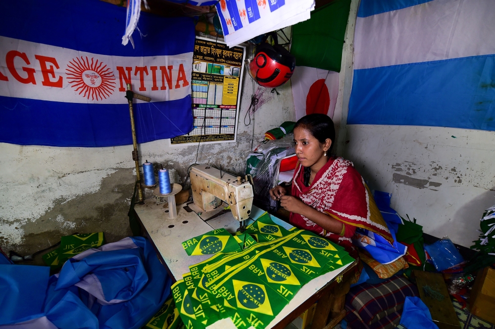 This photograph taken on May 17, 2018 shows a Bangladeshi worker sewing flag for world cup football playing nations in Narayanganj, on the outskirts of Dhaka, ahead of the 2018 football World Cup. AFP / Munir UZ ZAMAN 