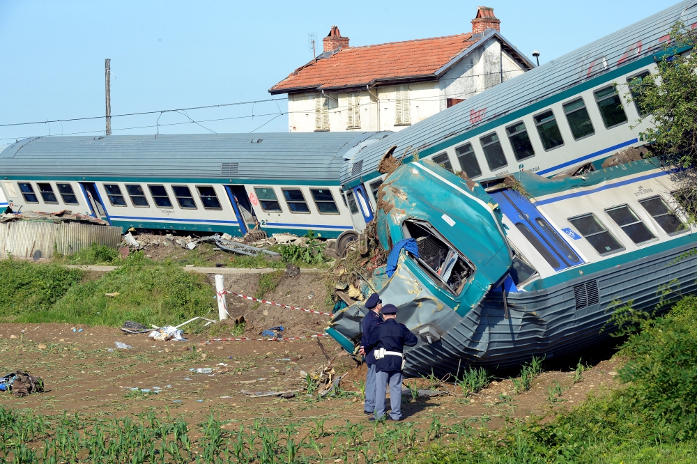 Italian police officers stand next to the twisted wreckage of a train that plowed into a truck last night in Caluso, near Turin, Italy, May 24, 2018. REUTERS/Massimo Pinca