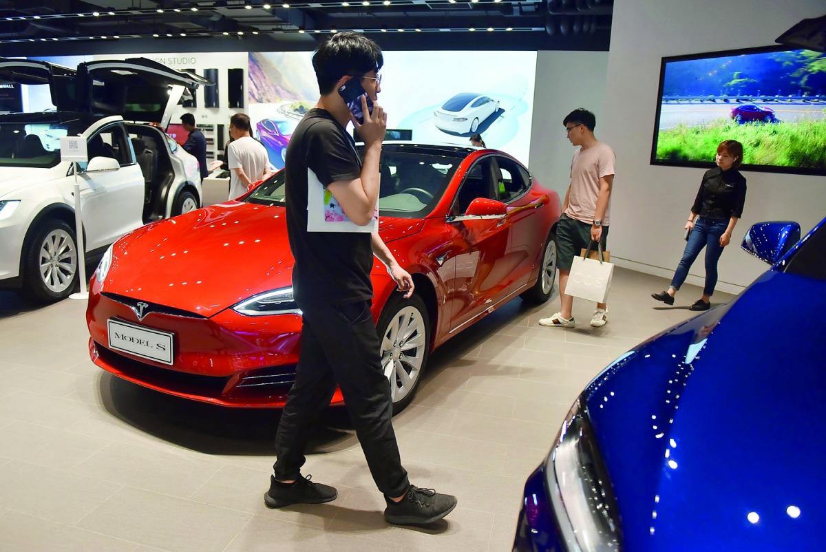 People look at cars in a Tesla showroom in Beijing on May 23, 2018. China announced on May 22 that it would cut tariffs on auto imports from July 1, the latest sign of a thaw in trade frictions with the United States. AFP / Greg Baker