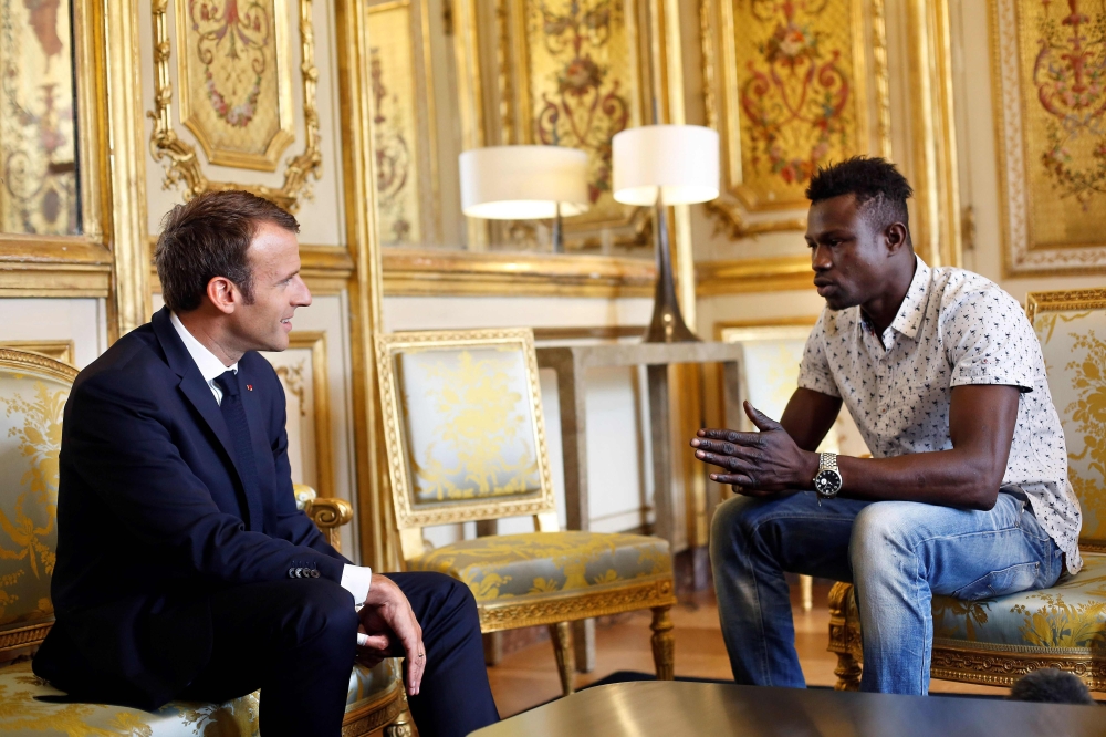 French President Emmanuel Macron (L) speaks with Mamoudou Gassama, 22, from Mali, at the presidential Elysee Palace in Paris, on May, 28, 2018. AFP / Pool / Thibault Camus
