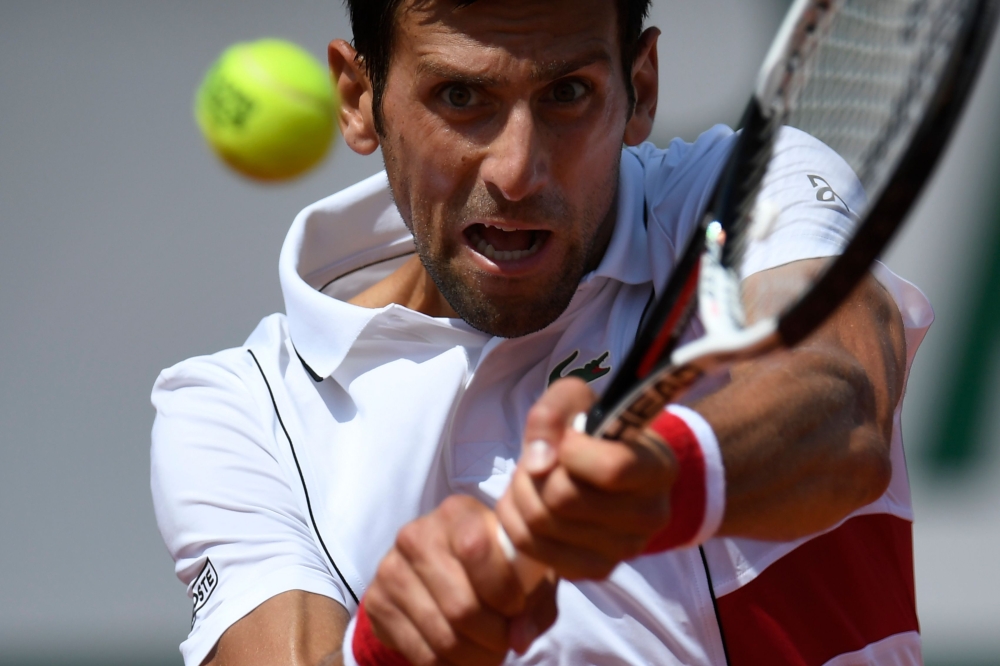 Serbia's Novak Djokovic plays a backhand return to Spain's Jaume Munar during their men's singles second round match on day four of The Roland Garros 2018 French Open tennis tournament in Paris on May 30, 2018. / AFP / CHRISTOPHE SIMON