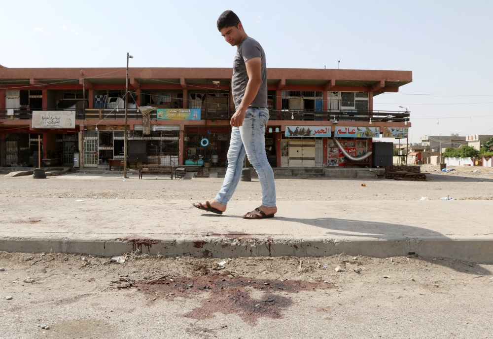 A man looks at bloodstains on a roadway after a bomb explosion in the ethnically-mixed Iraqi oil city of Kirkuk, Iraq, June 9, 2018. REUTERS/Ako Rasheed