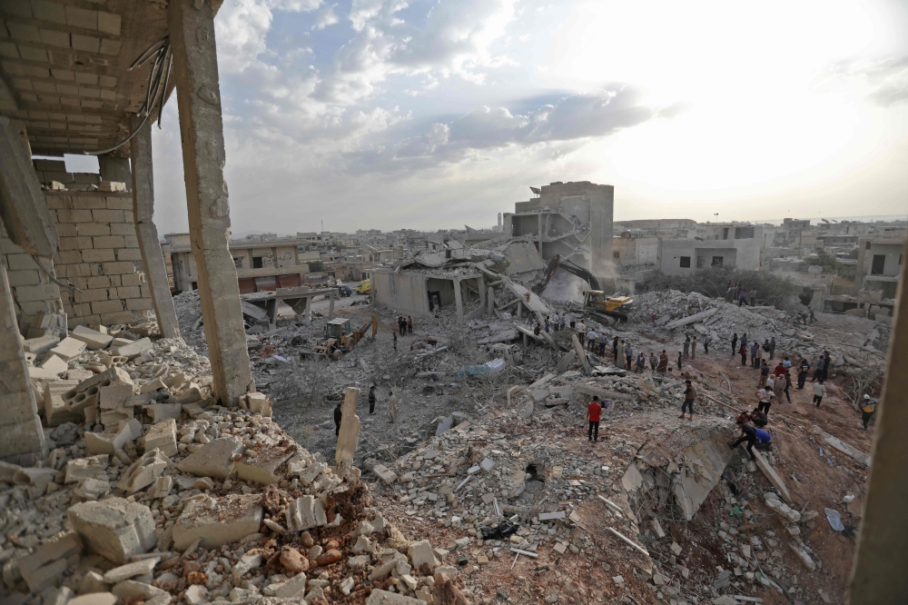 Syrians gather amidst destruction in Zardana, in the mostly rebel-held northern Syrian Idlib province, in the aftermath of following air strikes in the area late on June 8, 2018. AFP / OMAR HAJ KADOUR