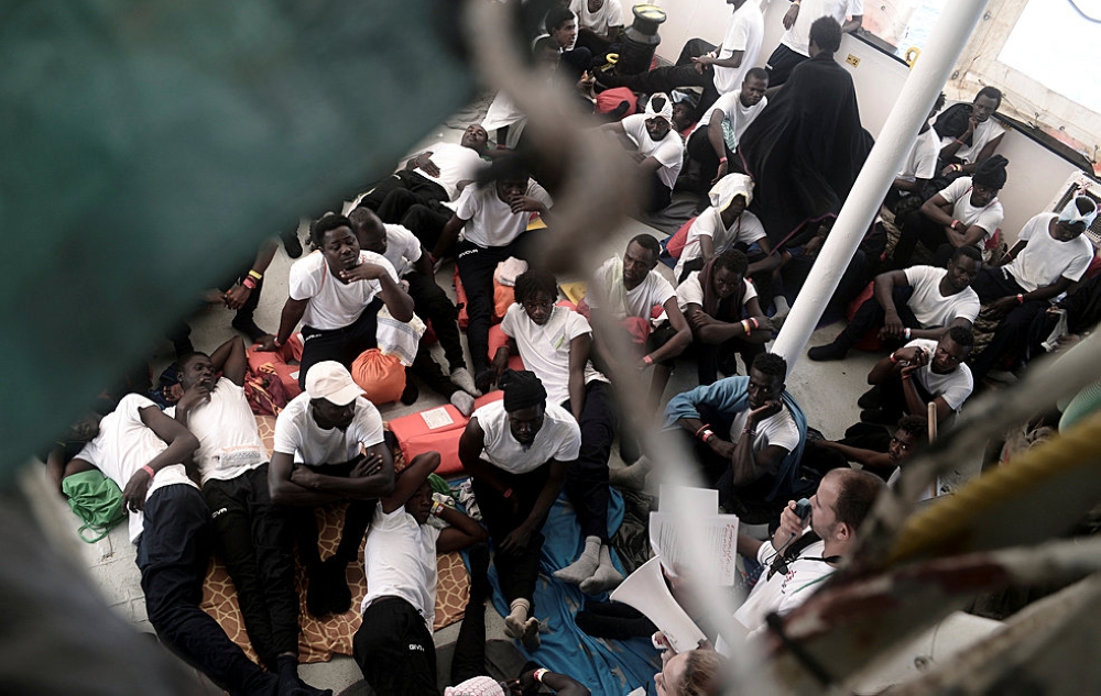Migrants sit on the deck of the MV Aquarius, a search and rescue ship run in partnership between SOS Mediterranee and Medecins Sans Frontieres in the central Mediterranean Sea, June 12, 2018. Karpov / SOS Mediterranee/Handout via Reuters 