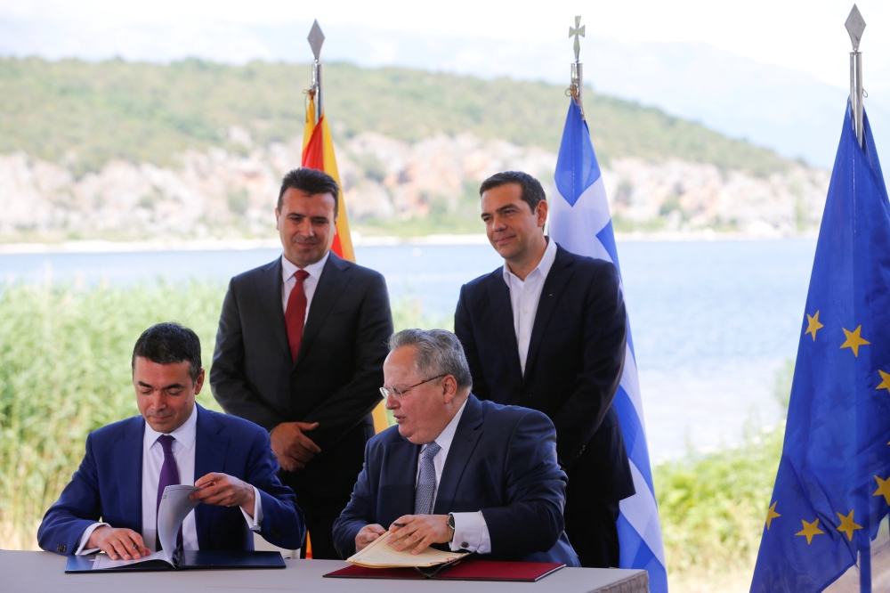 Greek Foreign Minister Nikos Kotzias and his Macedonian counterpart Nikola Dimitrov sign an accord to settle a long dispute over the former Yugoslav republic's name as Greek Prime Minister Alexis Tsipras and Macedonian Prime Minister Zoran Zaev look on in