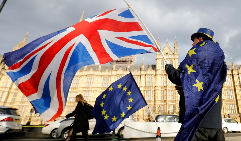 An anti-Brexit demonstrator waves a Union flag alongside a European Union flag outside the Houses of Parliament in London. (AFP / Tolga AKMEN)