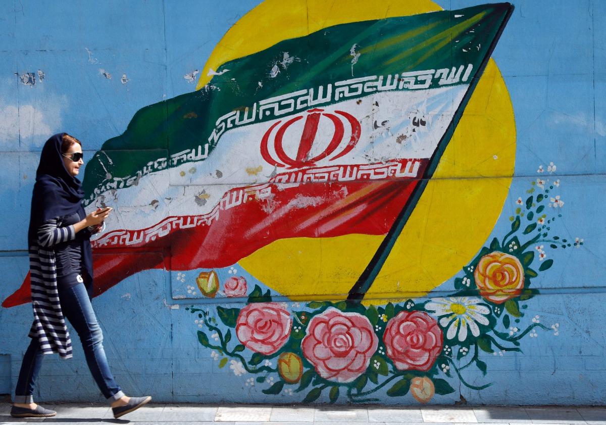An Iranian woman walks past a mural of the Iranian flag in the capital Tehran on October 14, 2017 (AFP) 