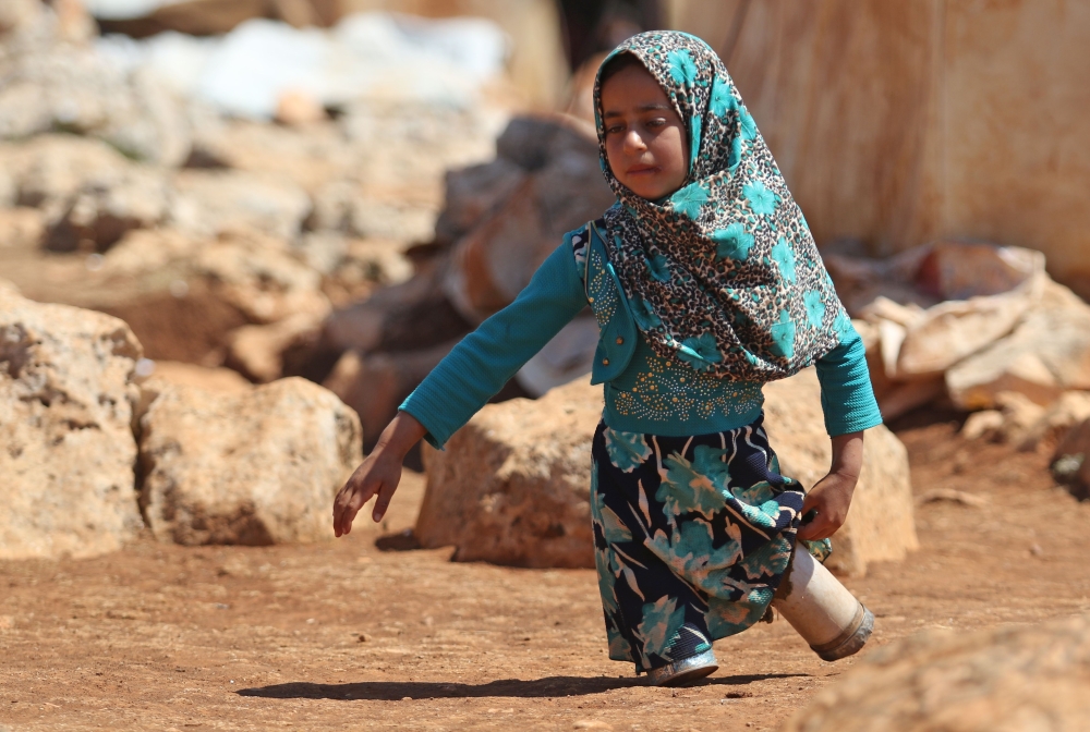 In this file photo taken on June 20, 2018 Eight year-old Maya Mohammad Ali Merhi walks using prosthetic legs made by her father from tin cans in a camp for displaced people, in the northern Syrian province of Idlib. (AFP / Aaref WATAD)