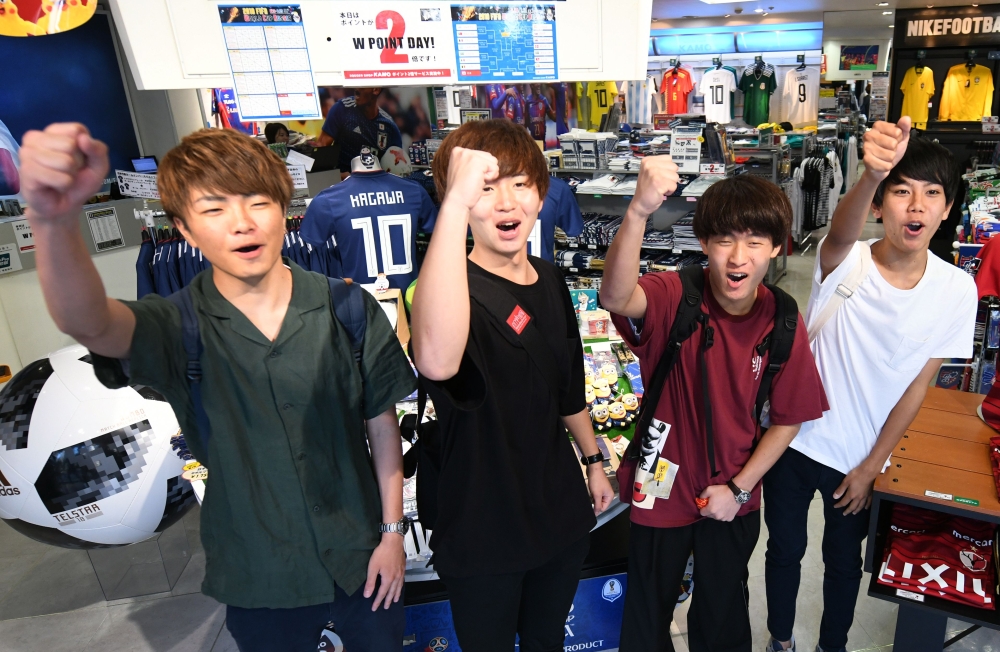 Customers cheer for Japan's national football team at a football sporting goods shop in Tokyo on July 2, 2018. / AFP / Kazuhiro NOGI 
