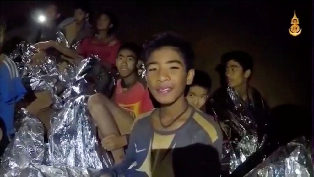 Boys from the under-16 soccer team trapped inside Tham Luang cave covered in hypothermia blankets react to the camera in Chiang Rai, Thailand, in this still image taken from a July 3, 2018 video by Thai Navy Seal. (Thai Navy Seal/Handout via REUTERS TV)