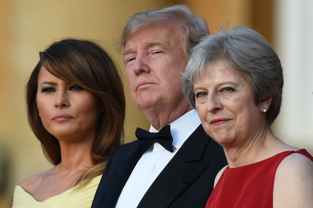 (L-R) US First Lady Melania Trump, US President Donald Trump and Britain's Prime Minister Theresa May stand on steps in the Great Court as the bands of the Scots, Irish and Welsh Guards perform a ceremonial welcome as they arrive for a black-tie dinner wi