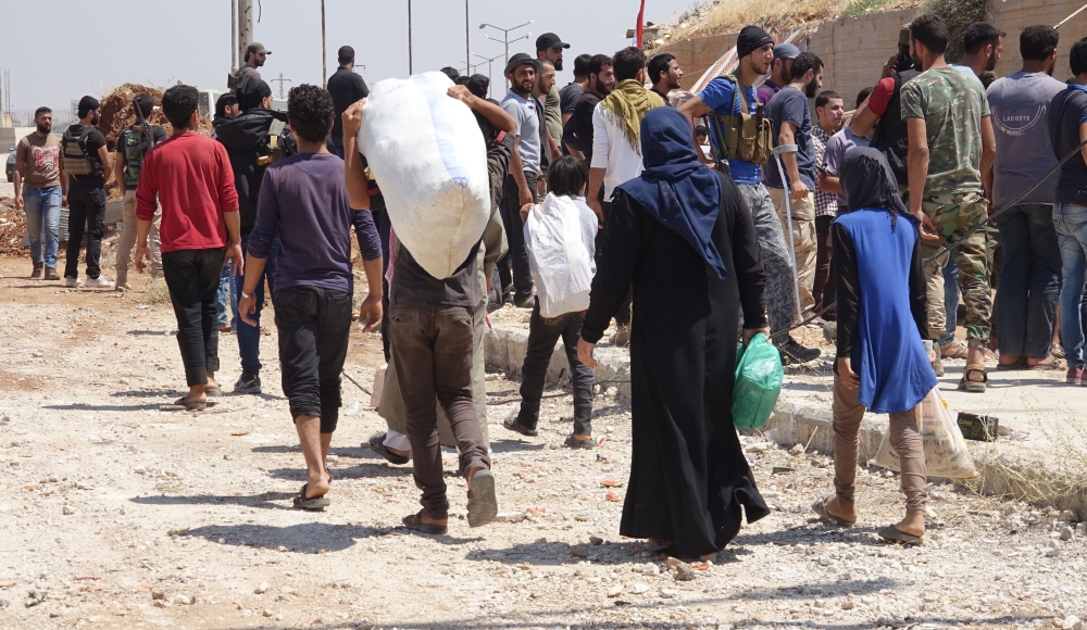 Syrian citizens are seen with their belongings as they wait to leave Syria’s southwestern Daraa province with the 1st convoy on July 15, 2018.  (Ammar Al Ali/Anadolu Agency)

