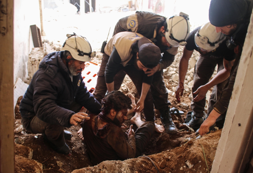 In this file photo taken on April 8, 2017, members of the Syrian civil defence volunteers, also known as the White Helmets, remove a victim from the rubble of his house, following a reported air strike by government forces on a rebel-held area in the sout