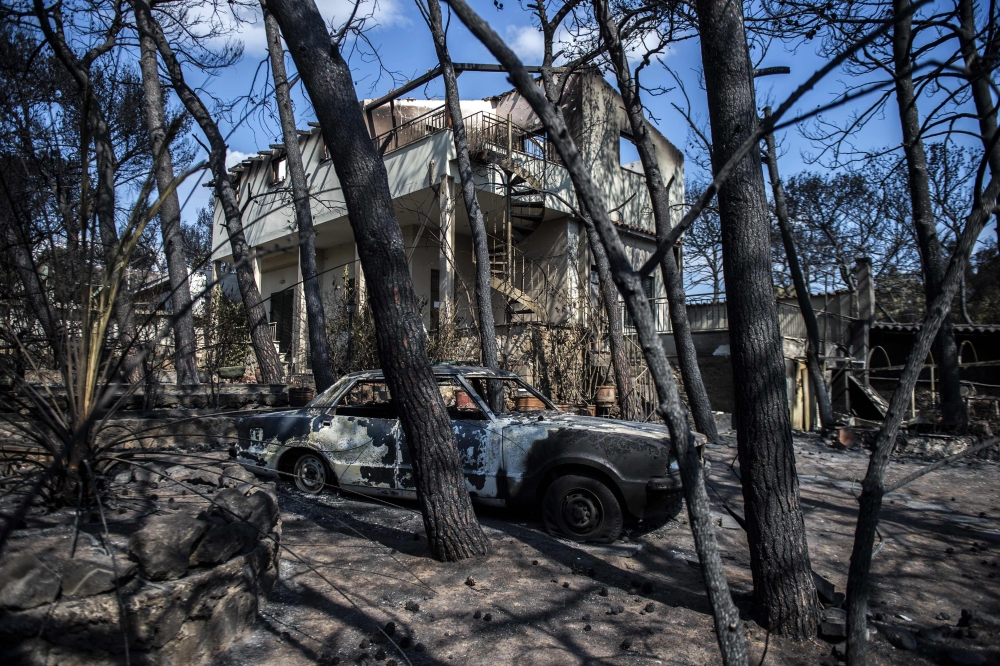 A photo taken on July 25, 2018 shows cars burnt following a wildfire in the village of Mati, near Athens. (AFP / ANGELOS TZORTZINIS)