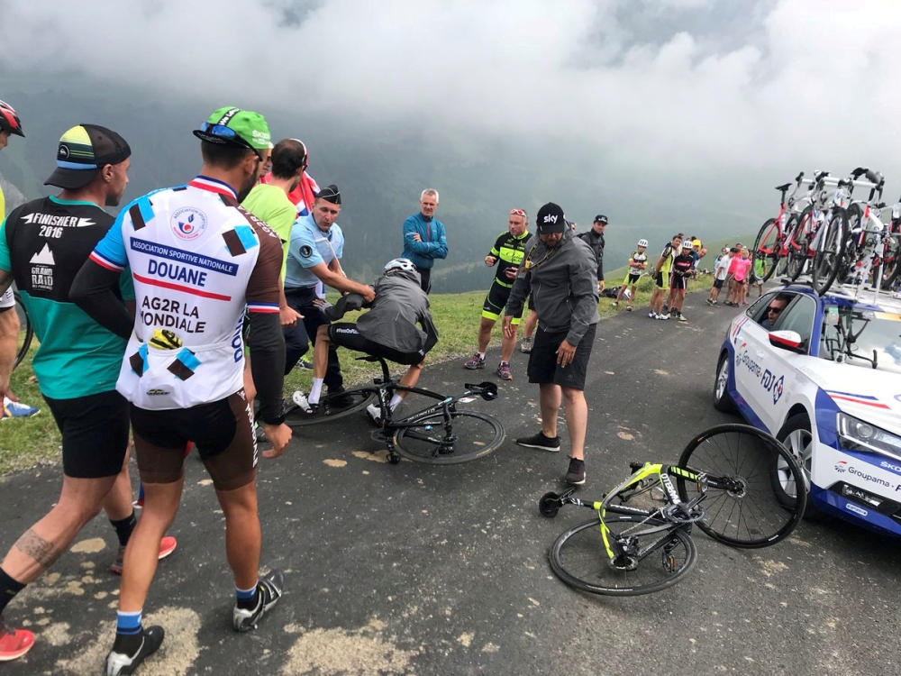 Team Sky rider Chris Froome of Britain who was mistaken for a fan is pulled off his bike by a police officer as he makes his way to the Team Sky bus from the summit finish on Col du Portet, Haute Pyrenees, France, July 25, 2018 in this picture obtained fr