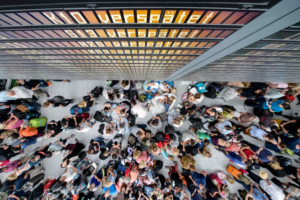 Travellers gather in front of information boards at the Terminal 2 at Munich airport on July 28, 2018 as around 200 flights had to be cancelled and two terminals evacuated after an unidentified person entered a secure area. AFP / dpa / Matthias Balk