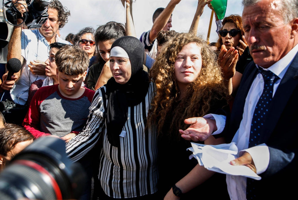 Palestinian activist and campaigner Ahed Tamimi (C) stands alongside her father (R), mother (C-L), and brother (L) upon her release from prison after an eight-month sentence for slapping two Israeli soldiers, in the West Bank village of Nabi Saleh on July
