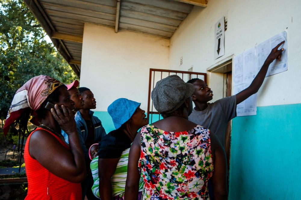 People gather a day after elections to look at ballot count results posted out side each polling station after vote counting was completed overnight, on July 31 2018 in Kambuzuma Township, Harare. (AFP / Jekesai NJIKIZANA)