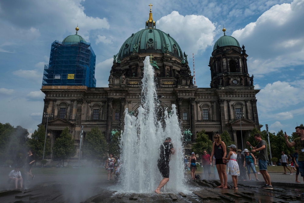 A man cools off in a fountain in front of the Berlin Cathedral as the heatwave in Europe continues with temperatures reaching 33 degrees Celsius in Berlin on August 4, 2018. (AFP / John MACDOUGALL)
