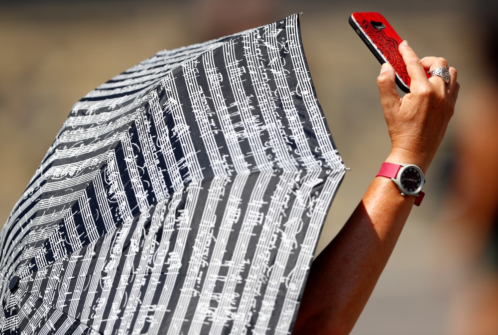A faithful takes a selfie as she waits for Pope Francis to lead the Angelus prayer as temperature soars throughout the country at the Vatican August 5, 2018. Reuters/Max Rossi