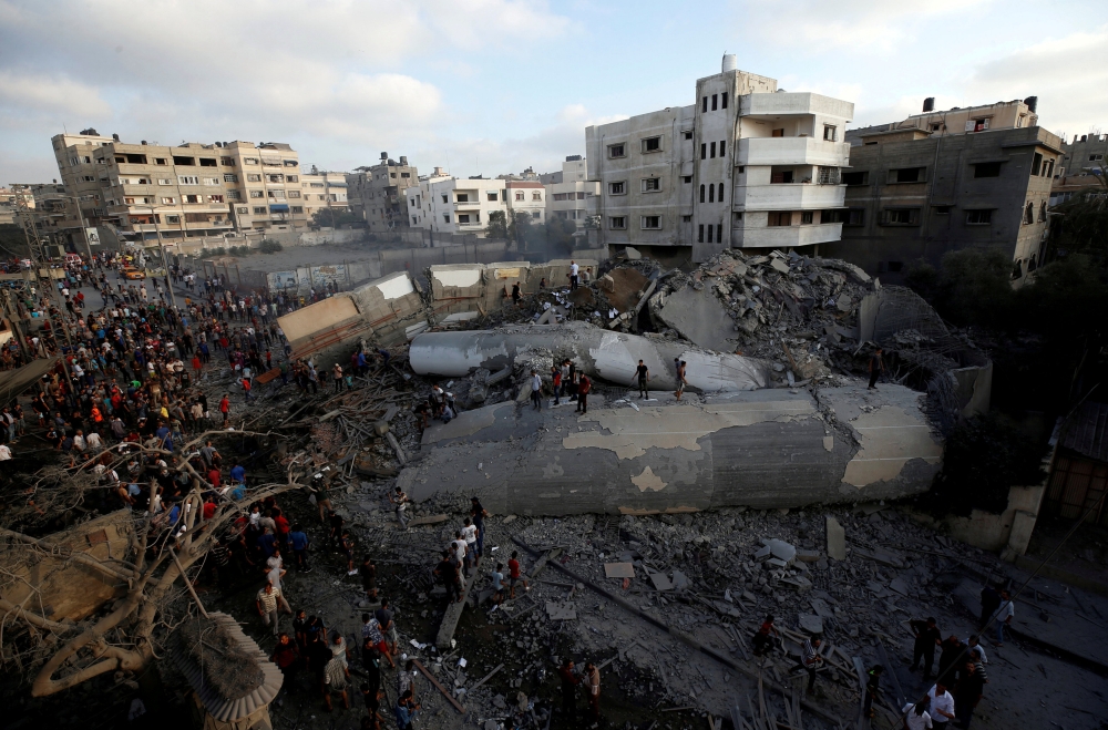 Palestinians gather around a building after it was bombed by an Israeli aircraft, in Gaza City August 9, 2018. REUTERS/Mohammed Salem 
