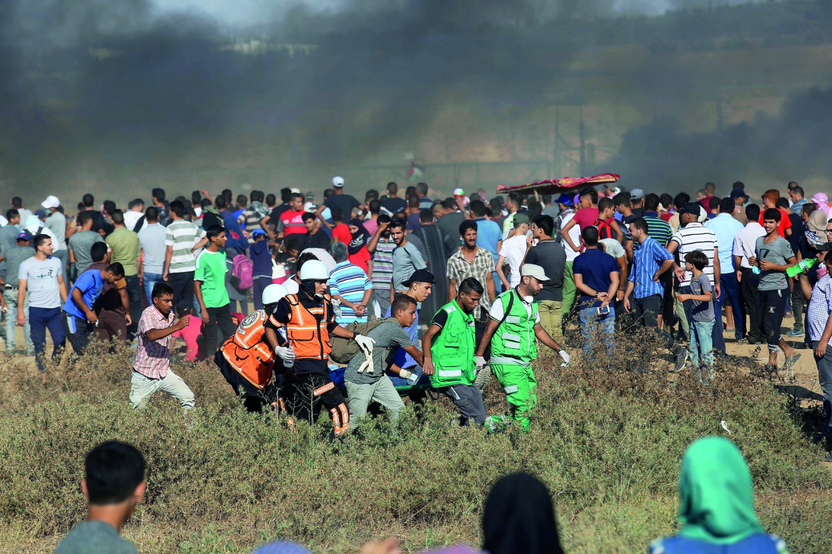Palestinian medics help a demonstrator who got injured after Israeli forces intervention on the 21st Friday of 