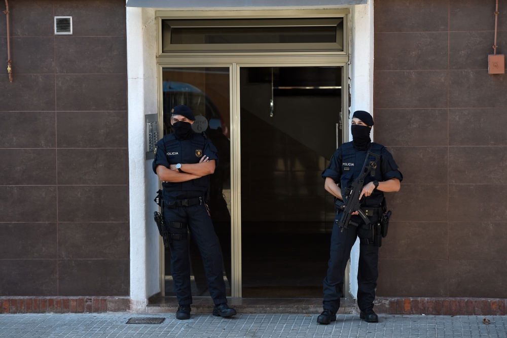 Catalan regional police (Mossos d'Esquadra) forces stand guard outside the apartment building of a man who tried to attack a police station in Cornella near the northeastern Spanish city of Barcelona on August 20, 2018.  / AFP / LLUIS GENE 